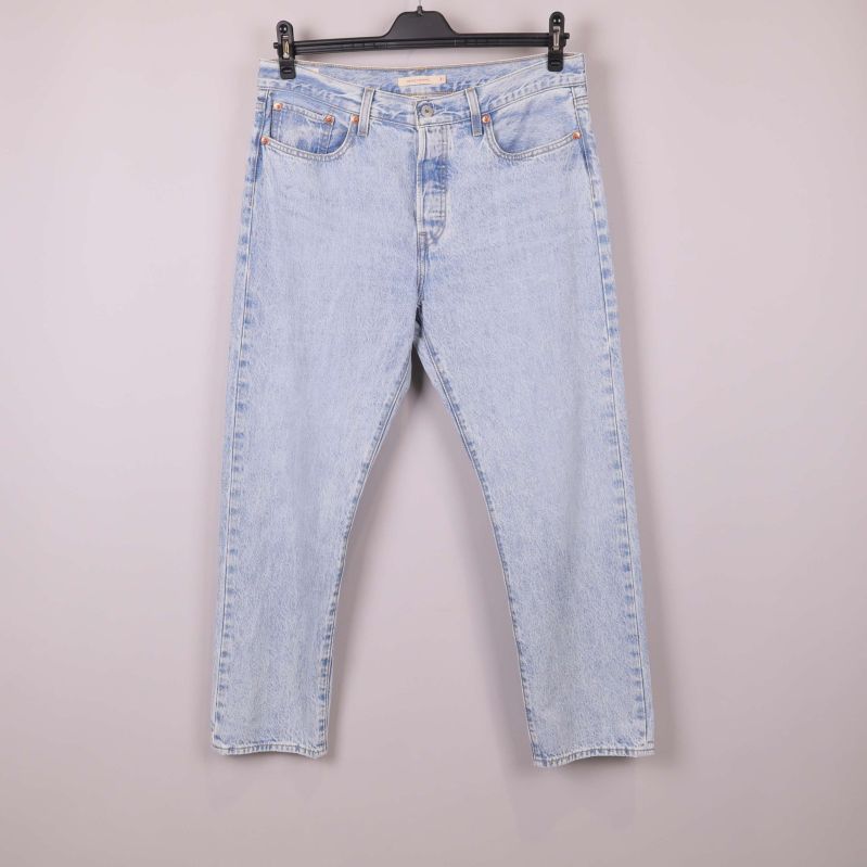 Jeans i ljusblå denim hänger på galge framifrån