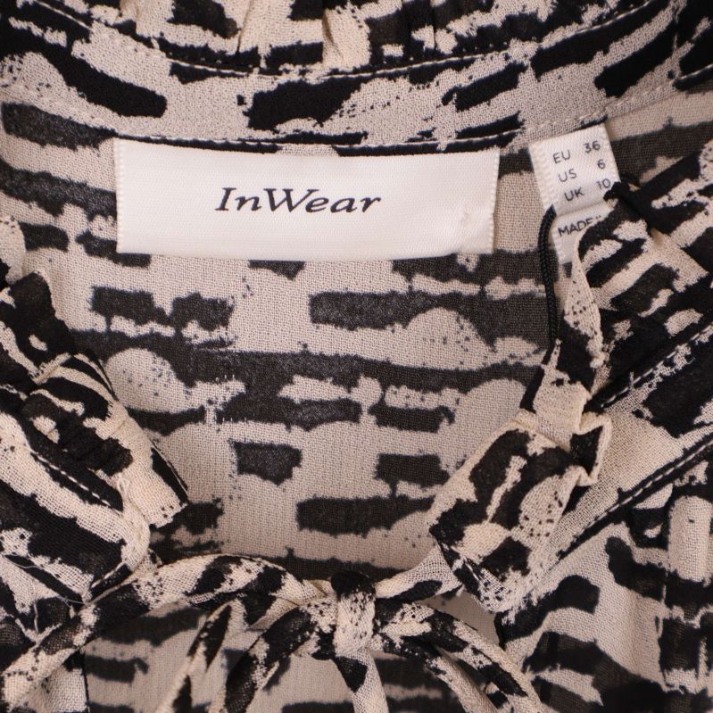 Närbild på InWear-logga och storleksetikett i blusens krage