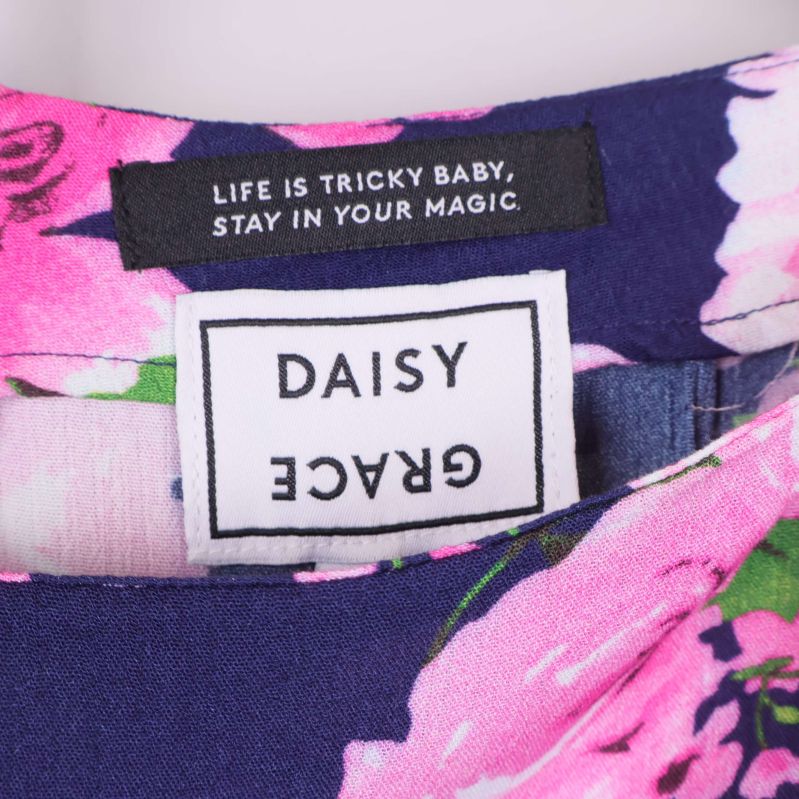 Närbild på märkning Daisy Grace i blommig kjol