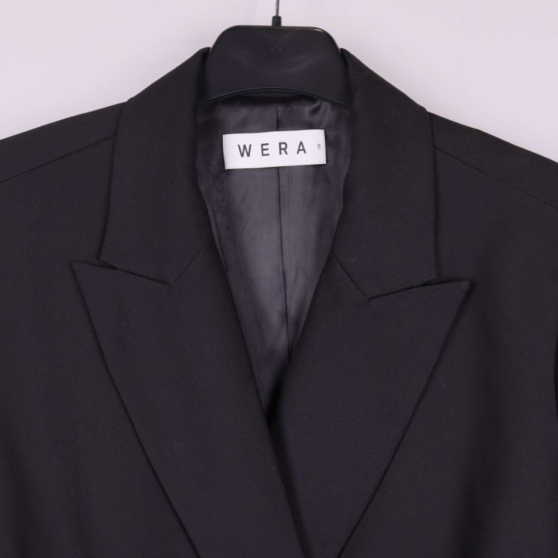 Närbild på krage och WERA-märke på svart blazer