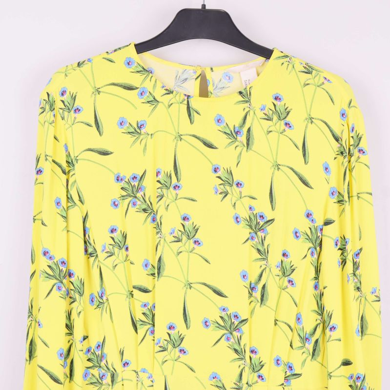 Närbild av gul klännings överdel med blå blommönster