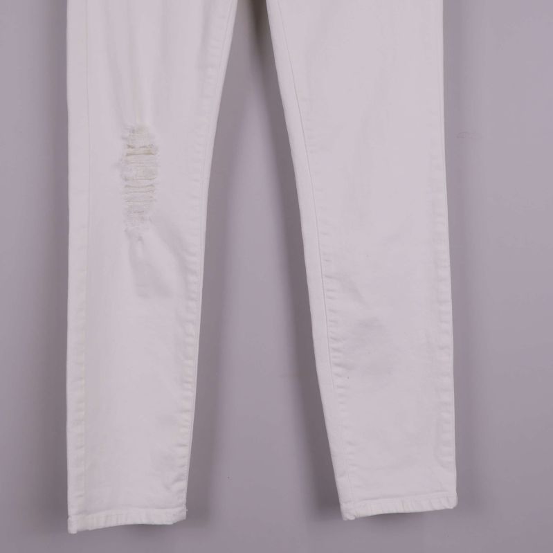 Detalj av ben med slitning och svag fläck på vita jeans