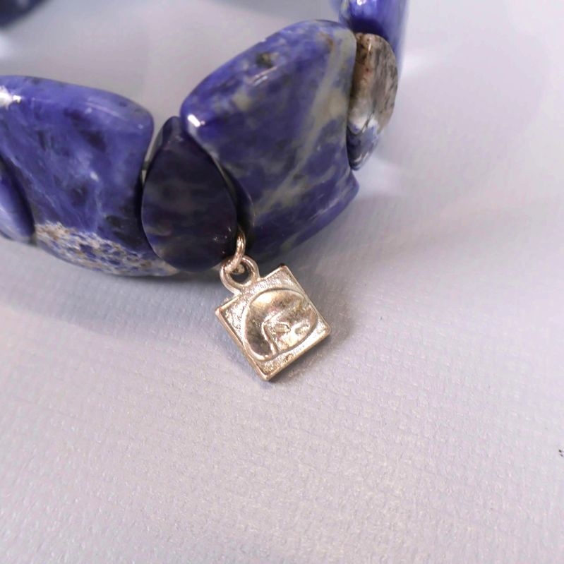 Närbild på silverfärgat hänge på stenarmbandet