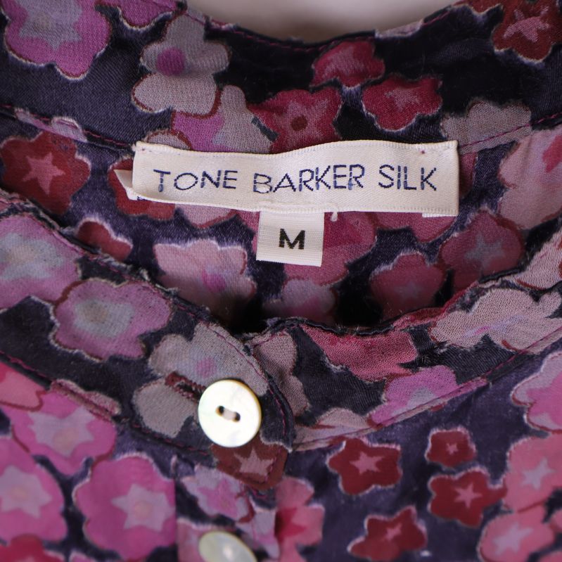 Närbild på Tone Barker Silk-märket och storlek M i kragen