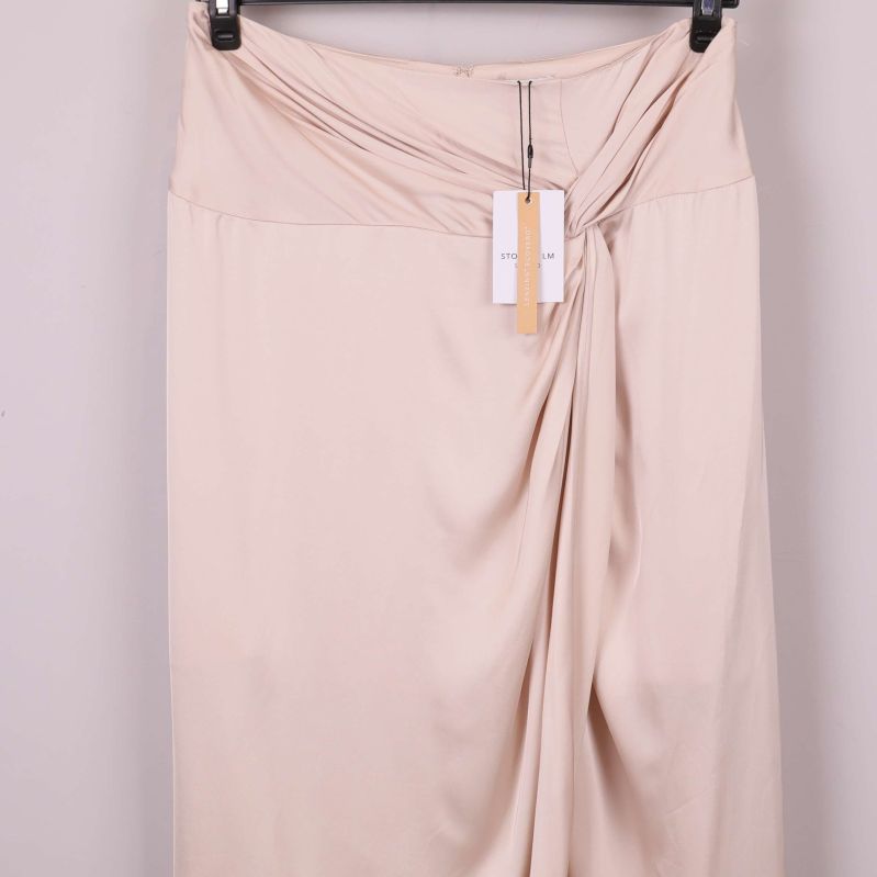 Närbild på draperad midjedetalj på ljus kjol