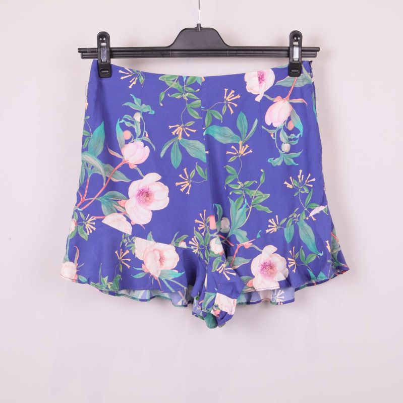 Framsidan av blå shorts med blommigt mönster och volangkant