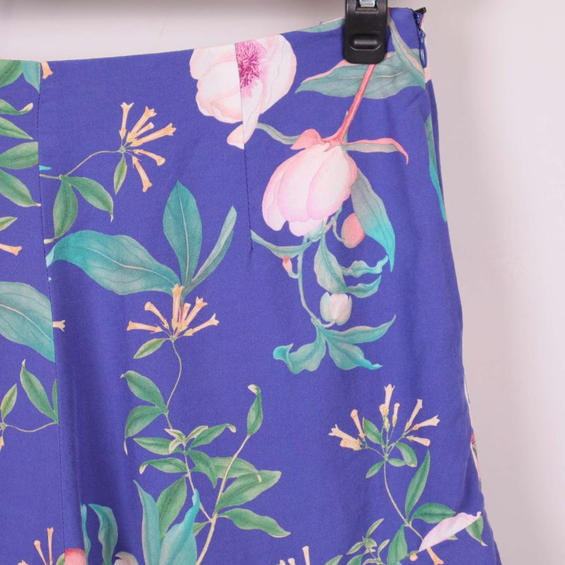 Närbild på blommönster och sömdetalj på blå shorts
