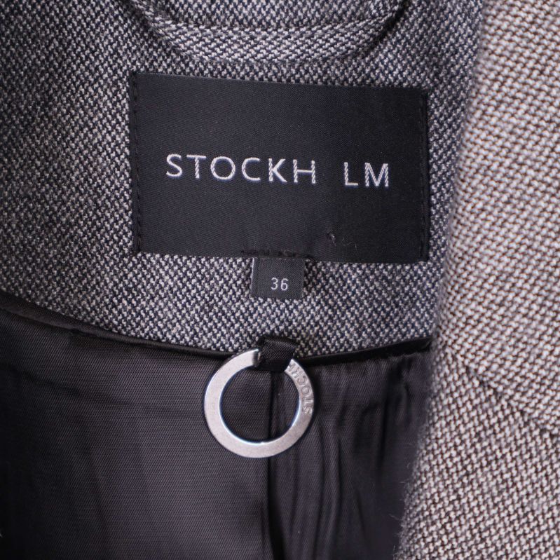 Etikett med STOCKH LM och storlek 36 i nacken på grå blazer