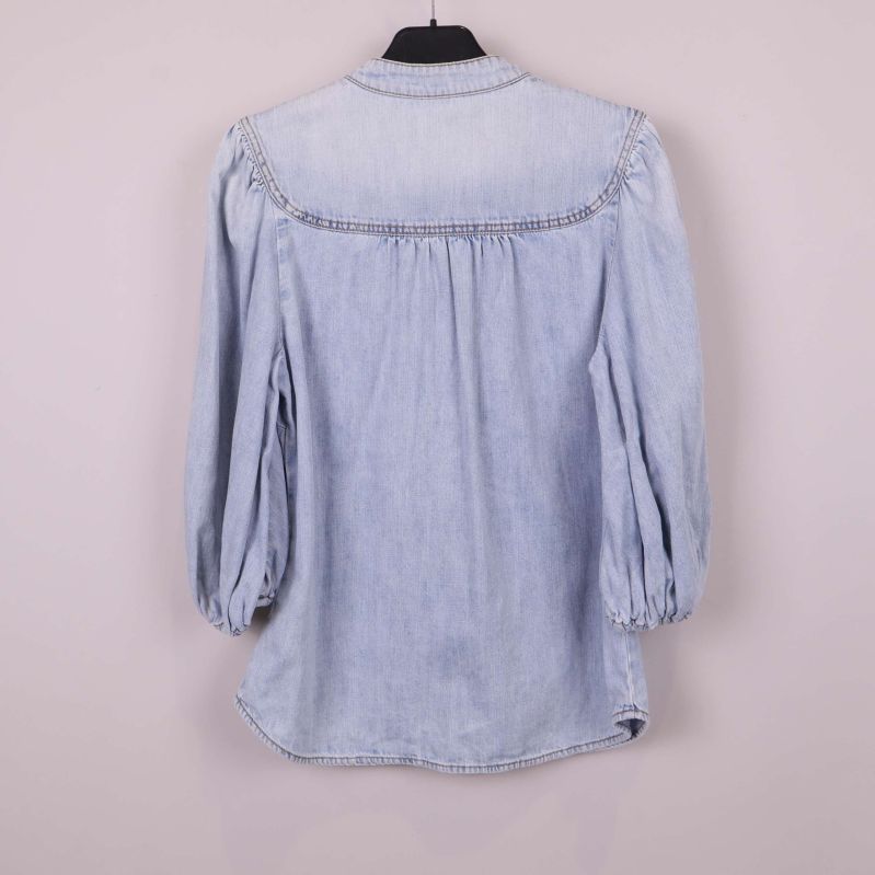 Baksida av ljus denimblus med puffärm