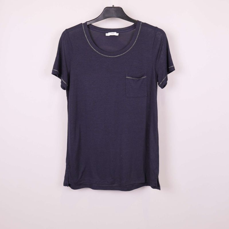 Blå t-shirt på galge mot ljus bakgrund, bröstficka synlig