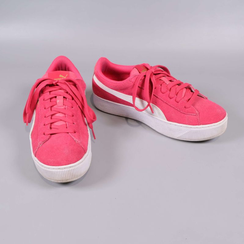 Sida av rosa Puma sneakers med vit sidorand