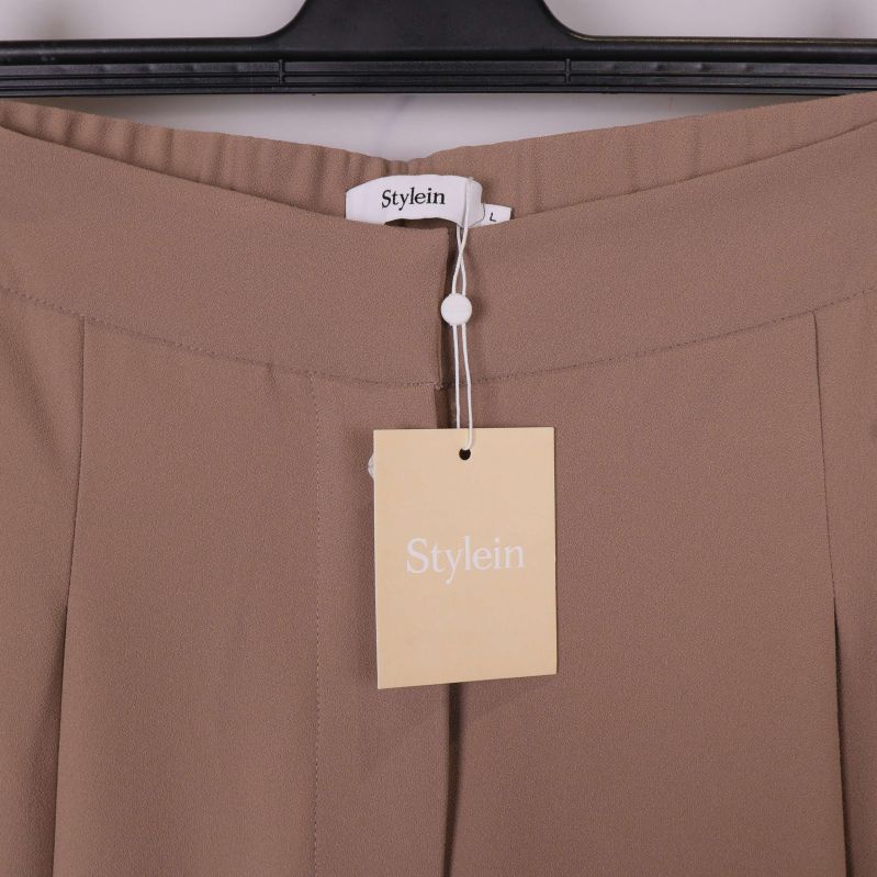 Närbild på midja och Stylein-hängare på beige byxa