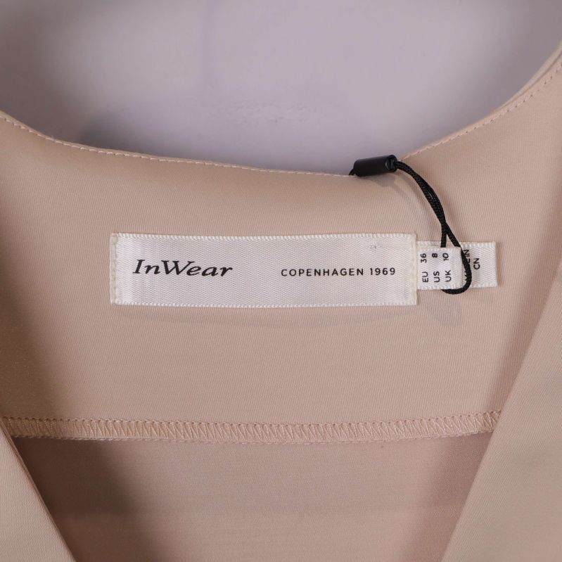 Närbild på InWear-märkesetikett i halsen på beige topp