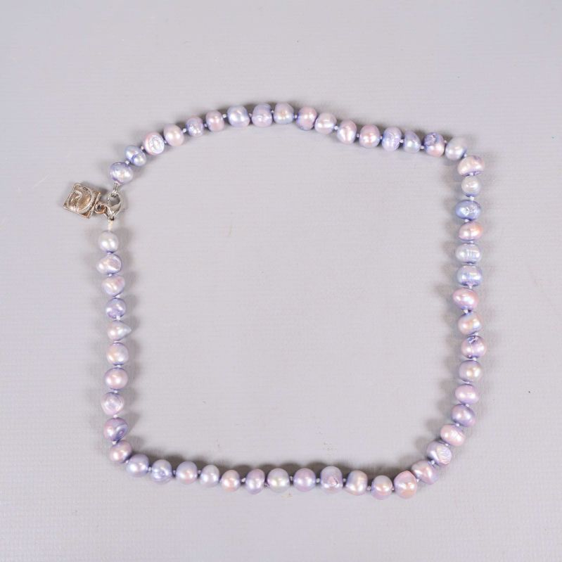 Halsband med lila och rosa pärlor liggande på ljus yta