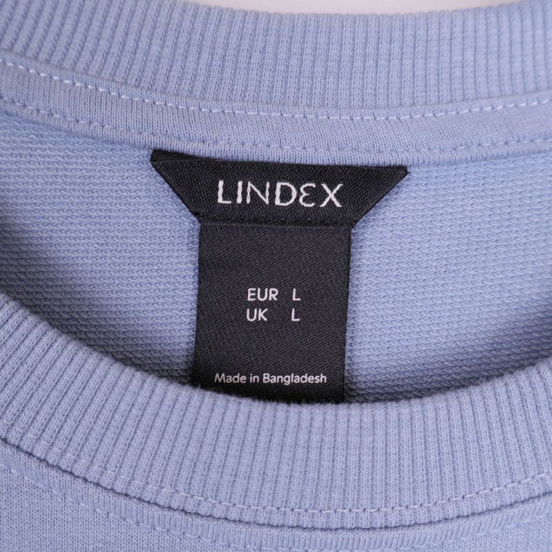Närbild på Lindex-lappen och ribbad krage på sweatshirt