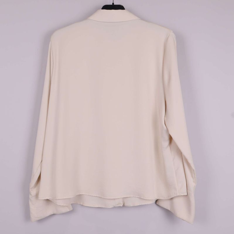 Baksida av beige blus med slät design och vida ärmar