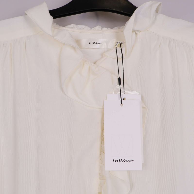 Närbild på blusens volang och varumärkesetikett InWear