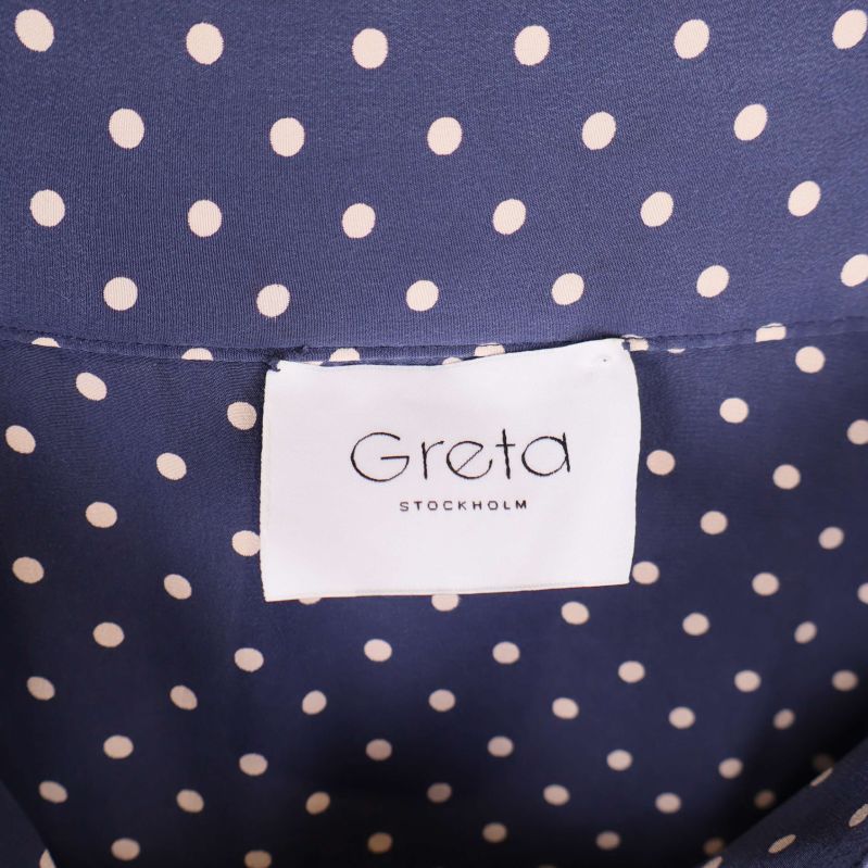 Etikett med Greta Stockholm i vit text
