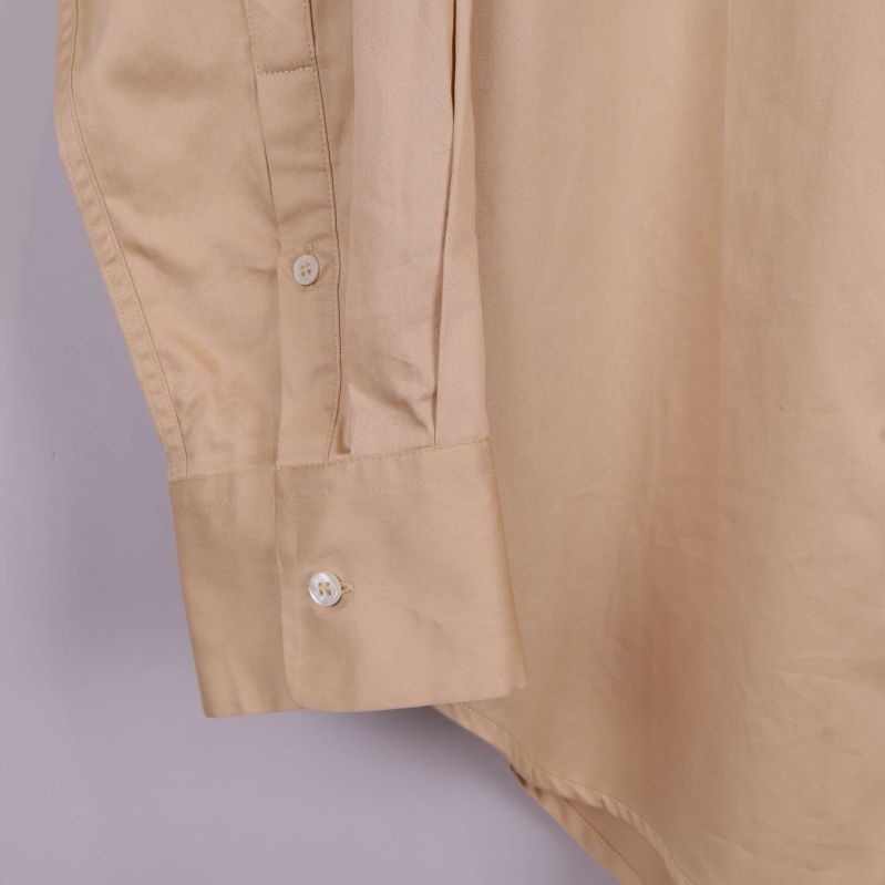 Närbild på skjortmanschett med knappar på beige tyg