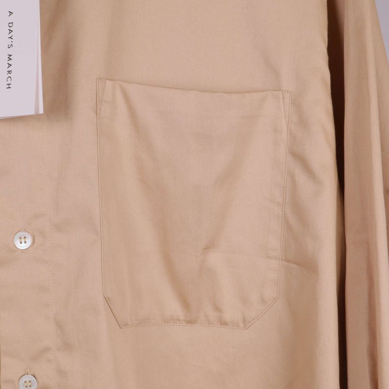 Närbild på bröstficka på beige skjorta