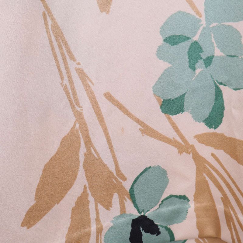 Närbild på blommigt tygmönster i blågrönt och beige