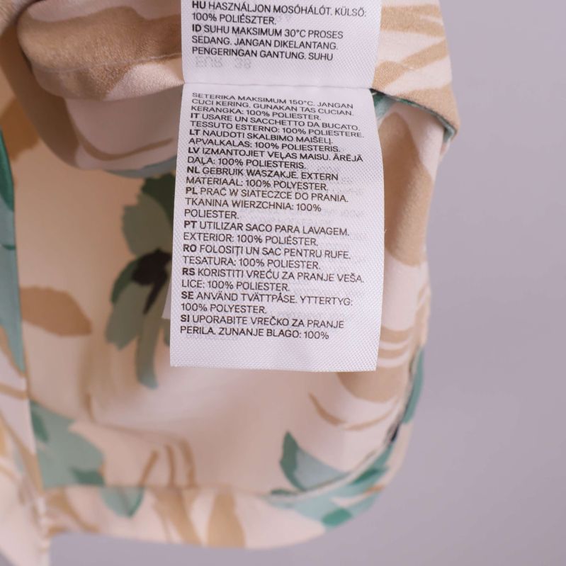 Materiallapp visar 100% polyester på flera språk