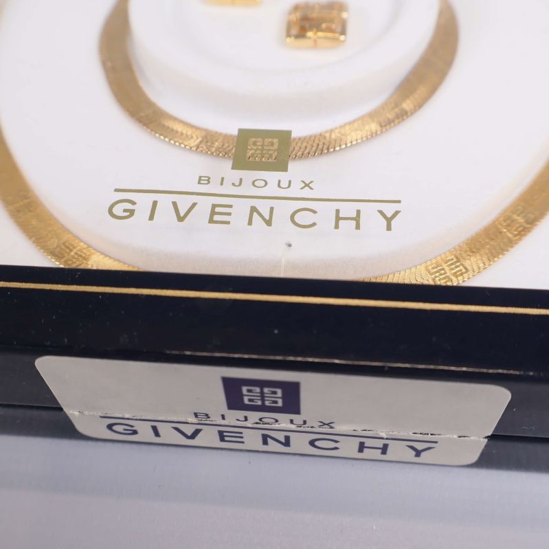 Närbild på Givenchy-logga och smycke med guldton