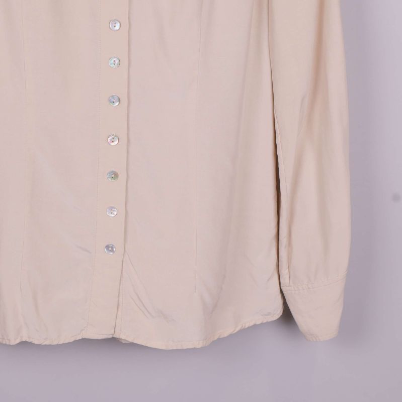 Detalj av ärmslut och nedre del på beige blus