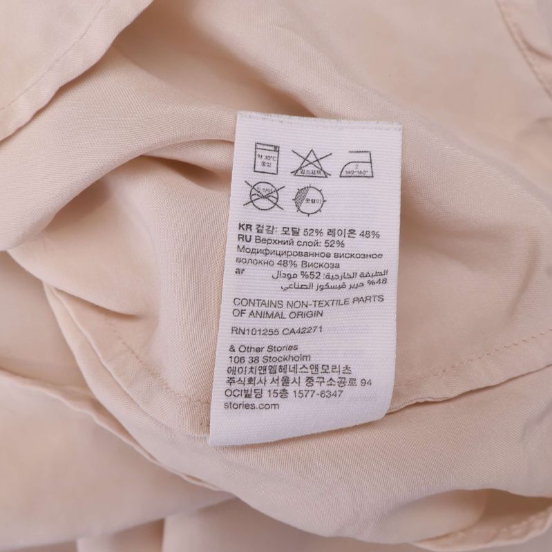 Materialetikett i beige blus med detaljerad materialinfo