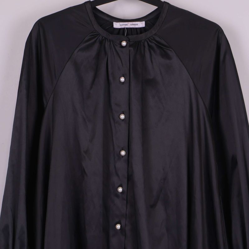 Närbild av övre framstycke med pärlknappar och rynk vid hals