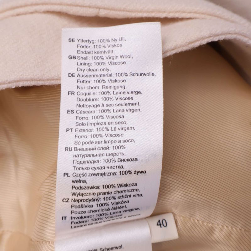 Textetikett som visar material: 100% ny ull, foder 100% viskos