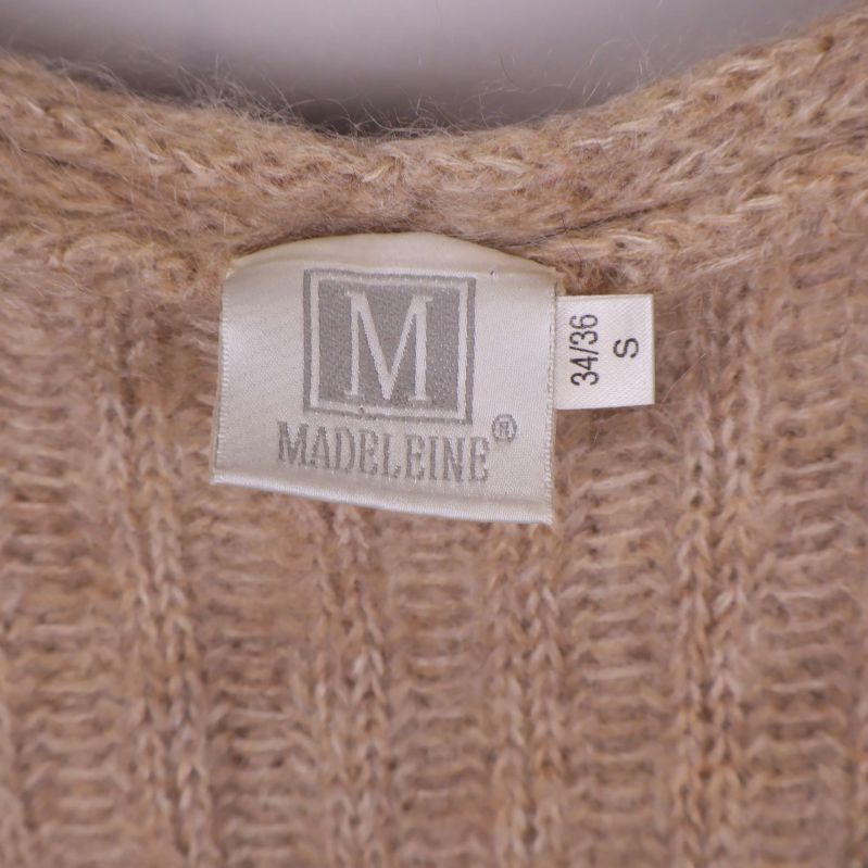 Närbild på Madeleine-märkesetikett och storlekslapp 34/36 S