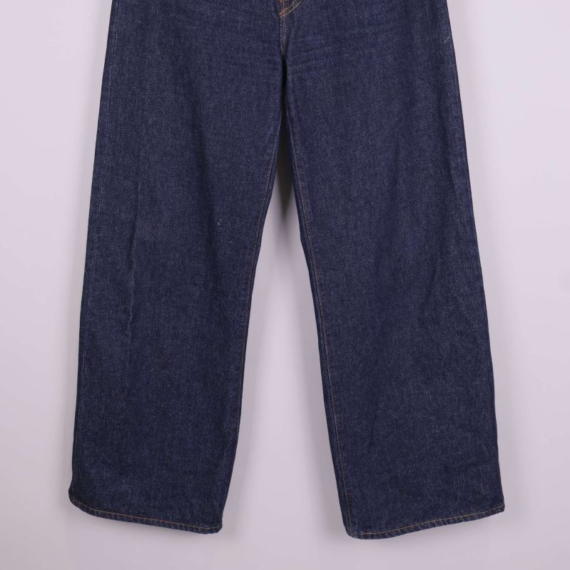 Ben och sömmar på vida mörkblå jeans