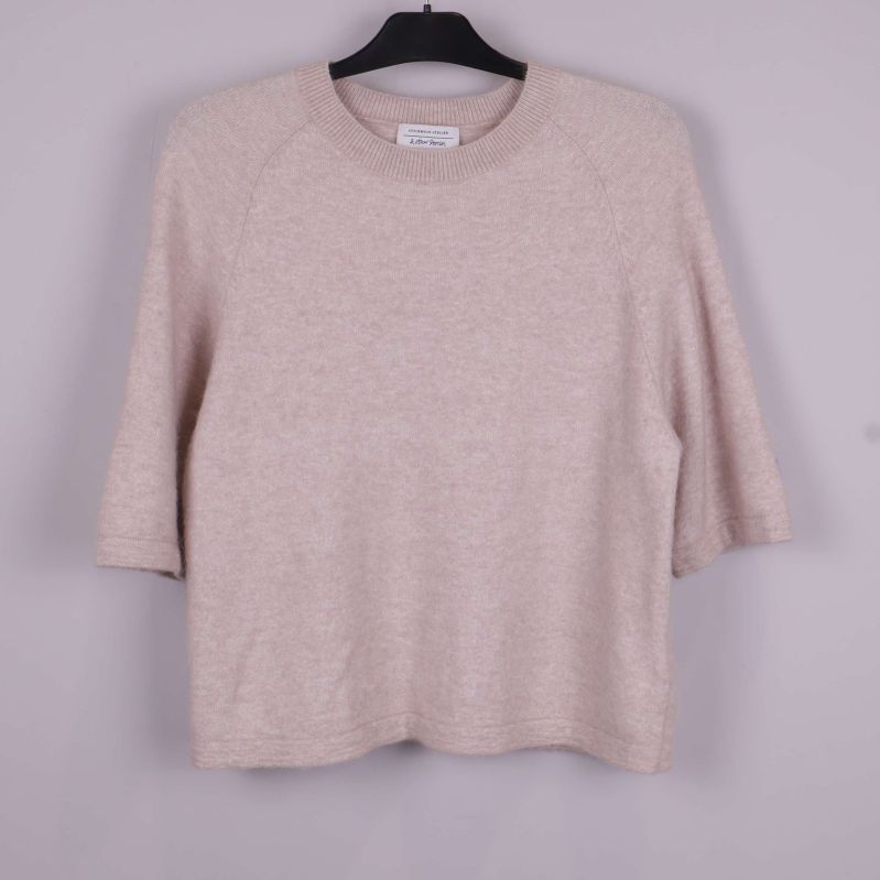 Stickad tröja i beige på galge framifrån