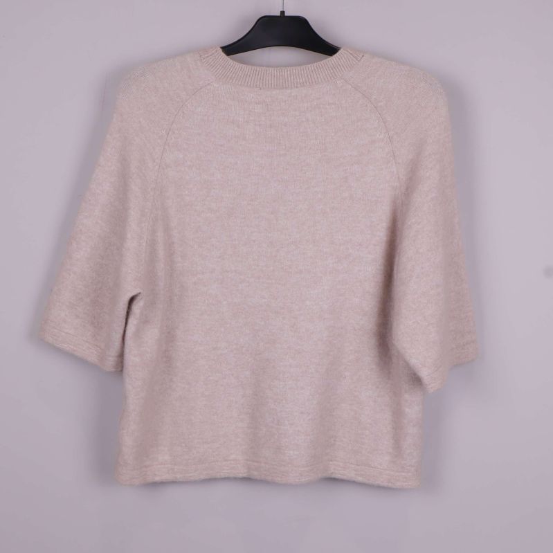 Stickad tröja i beige på galge bakifrån
