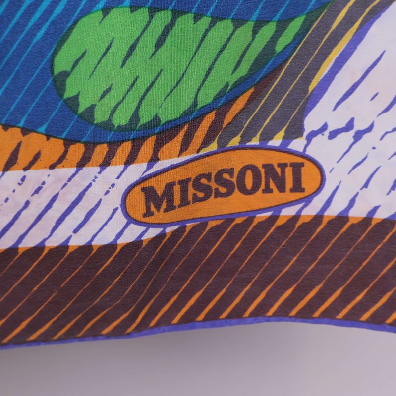 Närbild visar Missoni-märket på färgad scarfbakgrund