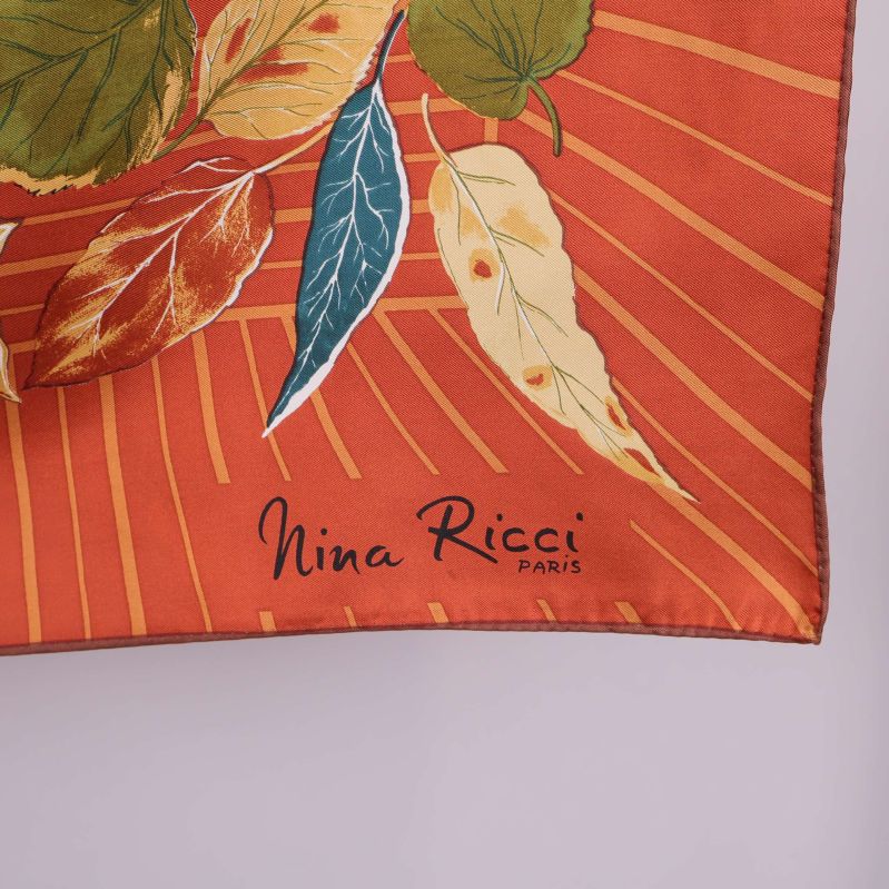 Närbild på hörn med Nina Ricci logga på scarfen
