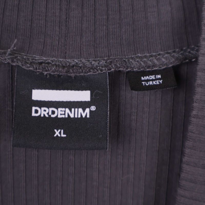 Närbild på Dr Denim logotyp och storlekslapp XL