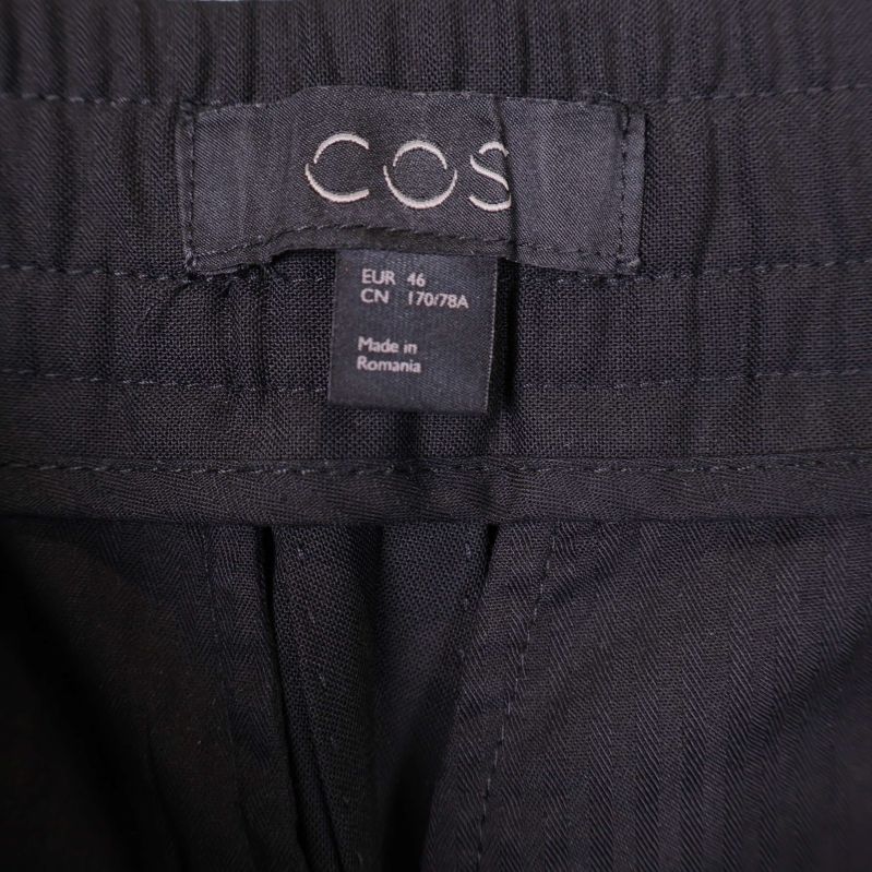 COS-label och storlekstagg i midjan på byxa