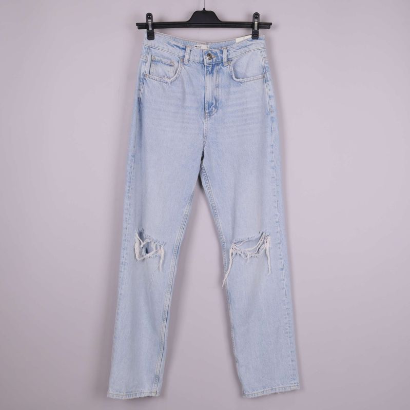 Framsida av ljusblå jeans med slitningar på knäna