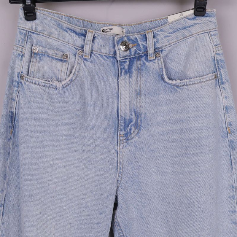 Närbild på midja och fickor framtill på slitna jeans