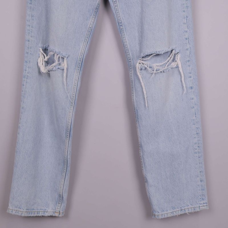 Slitna knän på ljusblå jeans i närbild