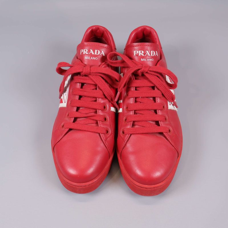 Framsidan av röda sneakers med vita logodetaljer