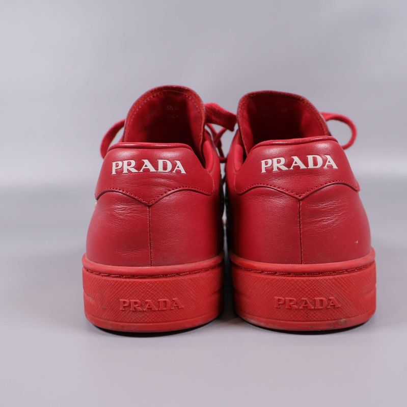 Baksidan av röda sneakers med embossad och tryckt PRADA-logga