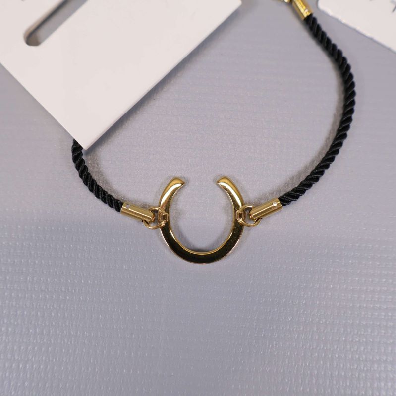 Närbild på hästskoformad gulddetalj på armbandet