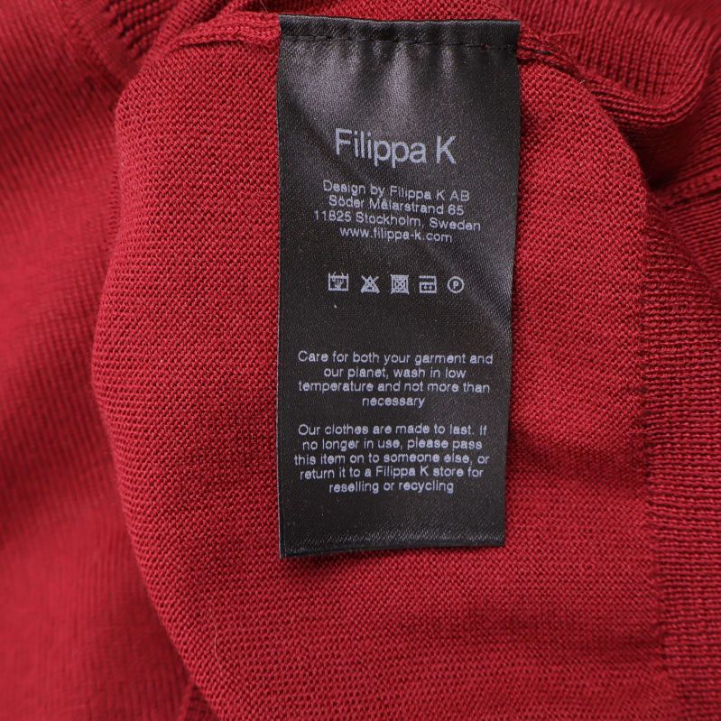 Svart vårdetikett från Filippa K på insidan av röd tröja