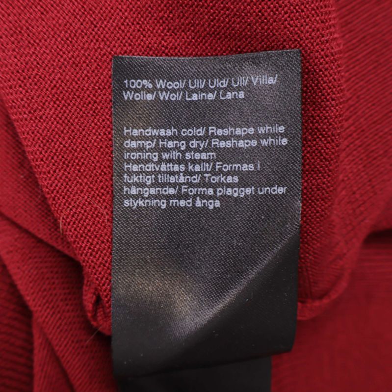 Materialetikett som visar 100% ull på röd tröja