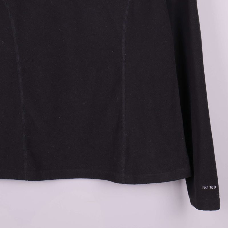 Detalj av svart fleece med TNF 100 text vid ärmslut