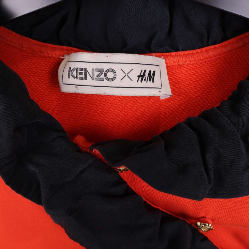 Närbild på Kenzo x H&M etikett och rynkad svart krage
