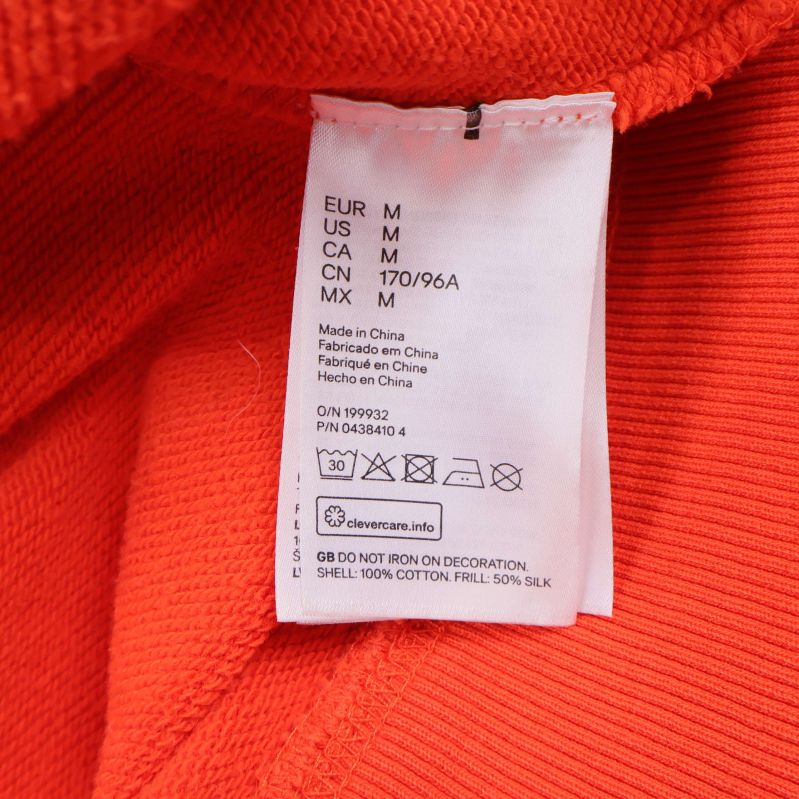 Materiallapp som visar 100 procent bomull på orange tröja